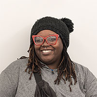 A person wearing red glasses and a gray shirtDescription automatically generated with low confidence